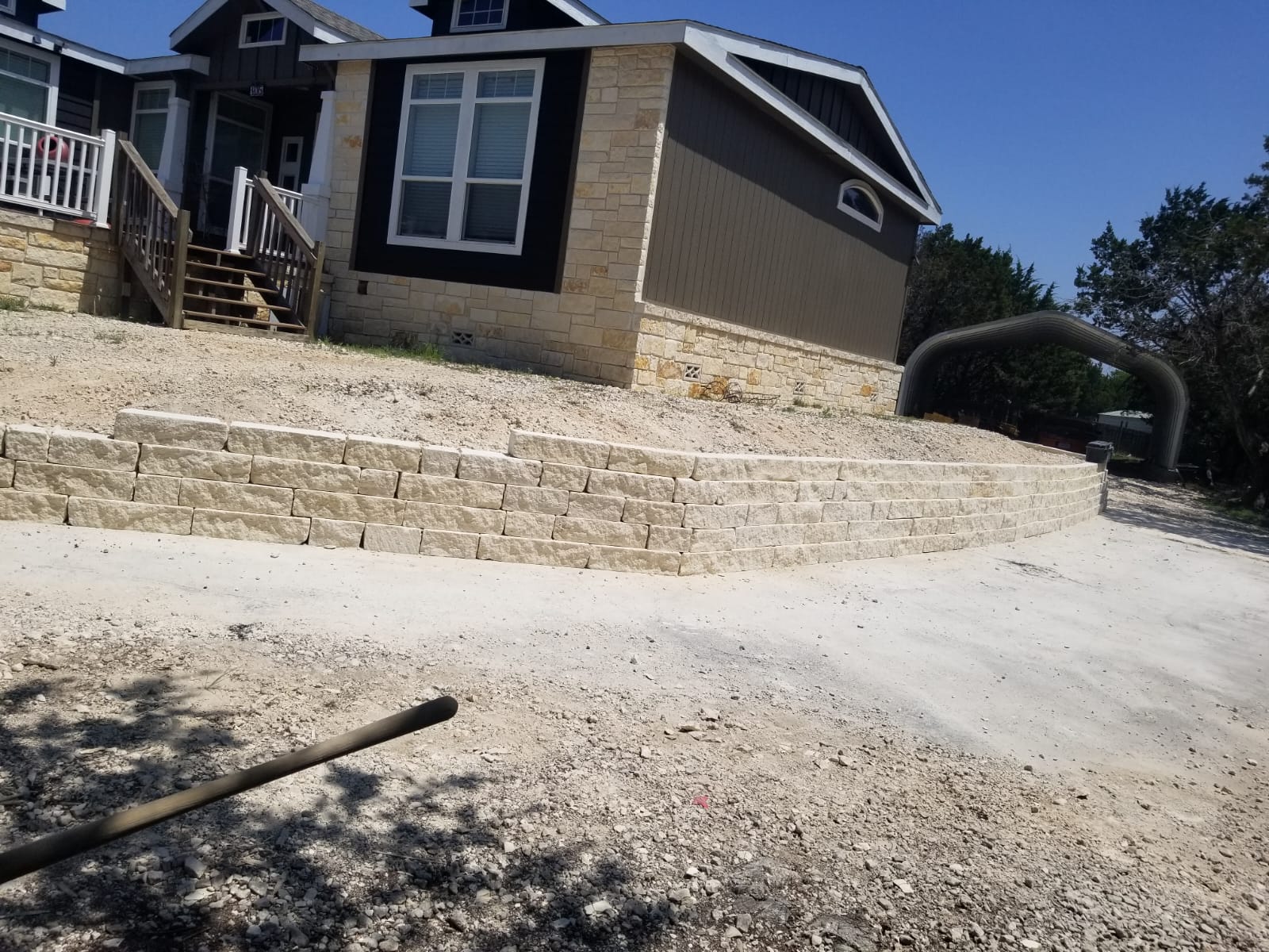 Long limestone retaining wall supporting a sloped front yard